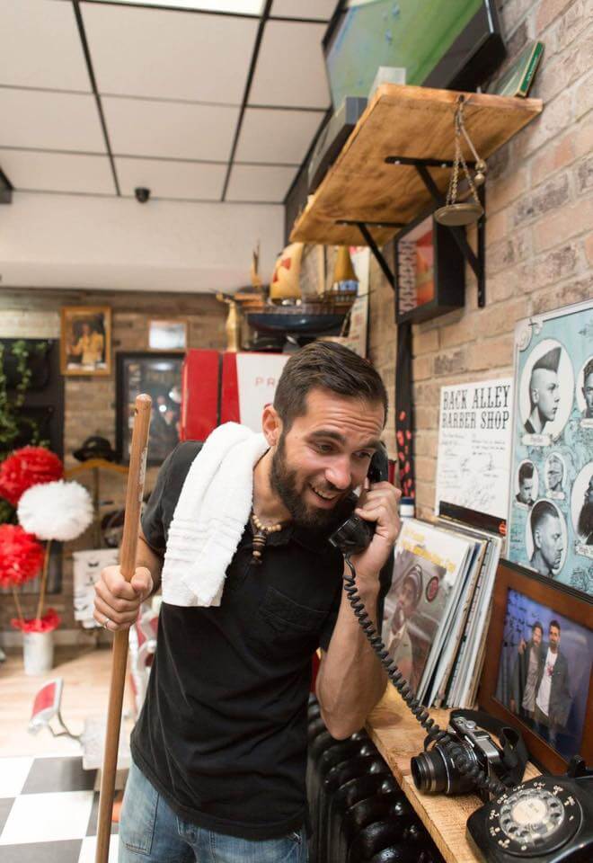 Man with beard answering the phone to book a hair appointment at Back Alley Barber Shop